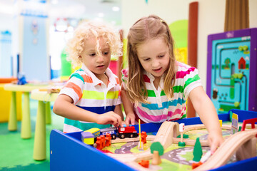 Naklejka premium Kids play wooden railroad. Child with toy train.