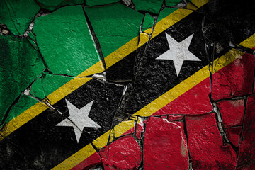 National flag of Saint Kitts and Nevis depicting in paint colors on an old stone wall. Flag  banner on broken  wall background.