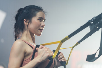 Asian female athlete doing exercise by use suspension training system.