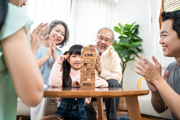 Asian big family cheering kid playing wooden block in the living room.