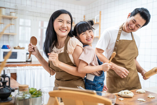 Asian family enjoy dancing and singing together while cooking at home.	