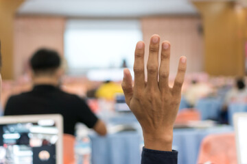 Audience raising hand while speaker on stage at conference to answer question while speaker speech at seminar hall with crowd groups in business and education concept