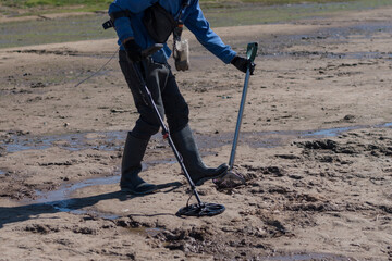 Man with a metal detector on a sea sandy beach.