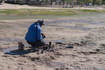 Man with a metal detector on a sea sandy beach.