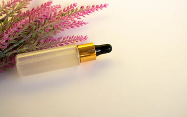 A bottle of cosmetic liquid transparent gel next to a branch of artificial lavender on a white background. Flat styling style. Place for your text