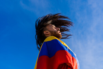 latin colombian man dressed with a colombian republic flag, with a painful face, artistic photo