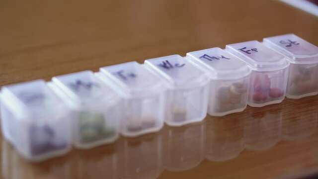 refocusing from distant to near of plastic organizer box for pills with cells marked black marker on days of week. Traditional and Alternative Medicine and health, disease, pandemic, covid-19 concept