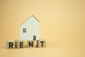 Wooden blocks with the letters RENT with wood home on top