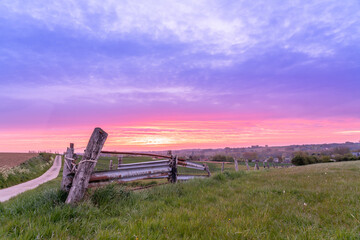 Fototapeta premium On the meadow with an iron fence with rising sun