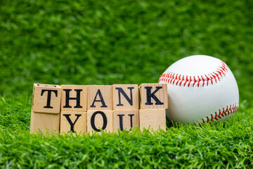 Baseball and thank you word are on green grass