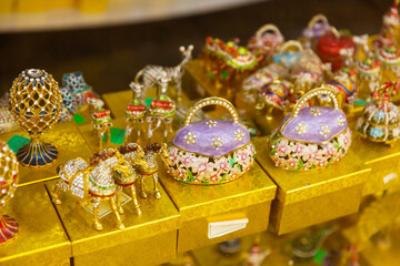 Fototapeta na wymiar Various colorful figures and figurines glazed with pearlized enamel and decorated with crystals on showcase of Tbilisi gift shop in Georgia..
