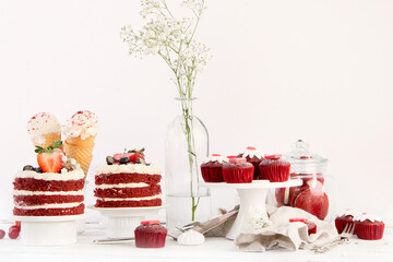 Delicious cake and cupcakes in red on white background. Table setting for celebration.