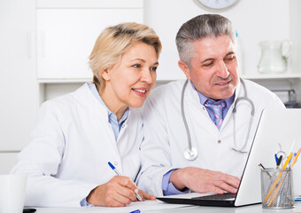 Doctor and nurse check patient data in hospital computer database