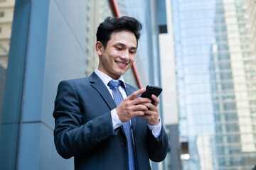 Young Asian businessman using smartphone to text message - Powered by Adobe
