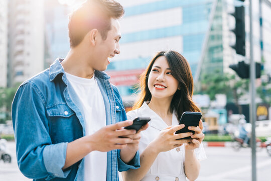 Young Asian couple using smartphone together on the street