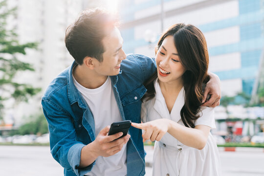Young Asian couple using smartphone together on the street