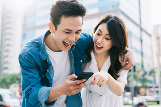 Young Asian couple using smartphone together on the street