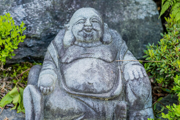 Miniature sitting Buddha in garden.