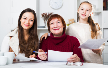 Three generations of happy family working together with documents at home