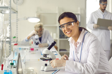 Building Successful Career in Science Research. Smart beautiful woman working in laboratory, using lab equipment, doing experiment, studying test samples. Portrait of happy scientist looking at camera - obrazy, fototapety, plakaty