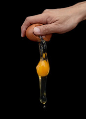 One hand chef breaking egg on black background cooking food object design