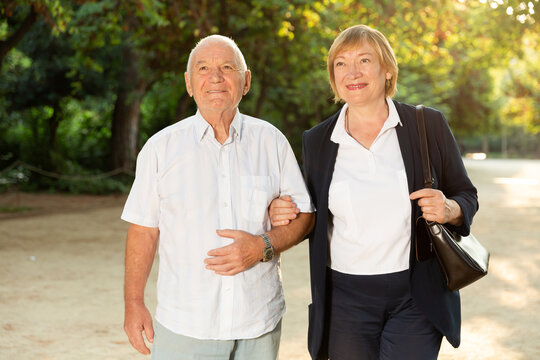 Fototapeta Cheerful senior couple walking in park on sunny summer day