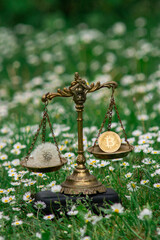 BITCOIN AND A DANDELION ON SCALES. CONCEPT: BITCOIN MINING ENERGY CONSUMPTION