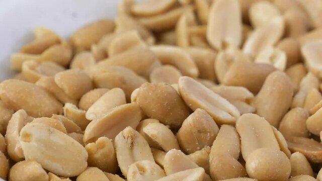 Eating peanuts out of a bowl, slider shot close up