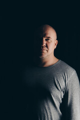 bald handsome man in gray clothes on black background