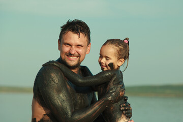 therapeutic mud for the body. mud baths on the lake. a man and a child are smeared with clay....