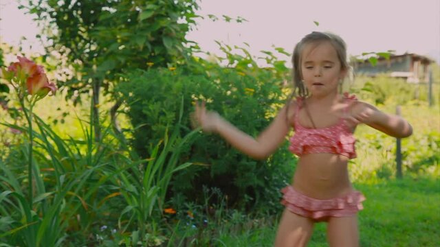 little girl in a swimsuit dancing in nature