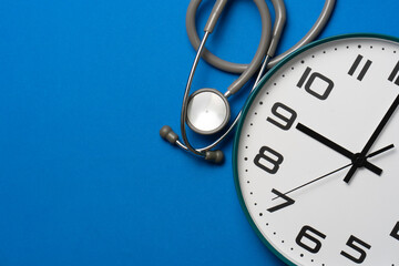 Top view of stethoscope and clock on the blue background, schedule to check up healthy concept