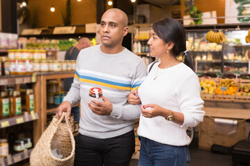 Casual latin american family couple doing shopping together in food department of supermarket