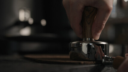 closeup of barista tamping fresh coffee in bottomless portafilter