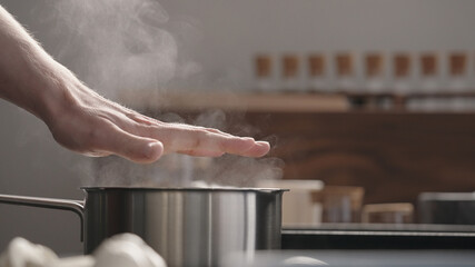 man hand check heat from saucepan
