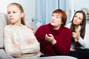 Frustrated girl sitting at home while mother and grandmother berating her