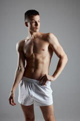 Fototapeta na wymiar man bodybuilder in white shorts gesturing with hands on gray background sport fitness model