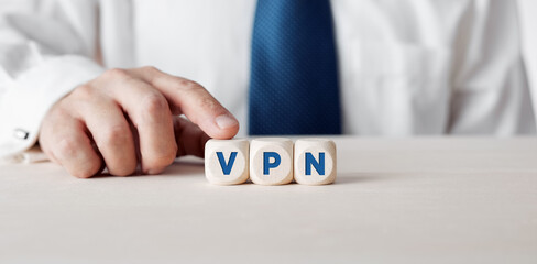 Businessman pressing his finger on the wooden cubes with the word VPN.