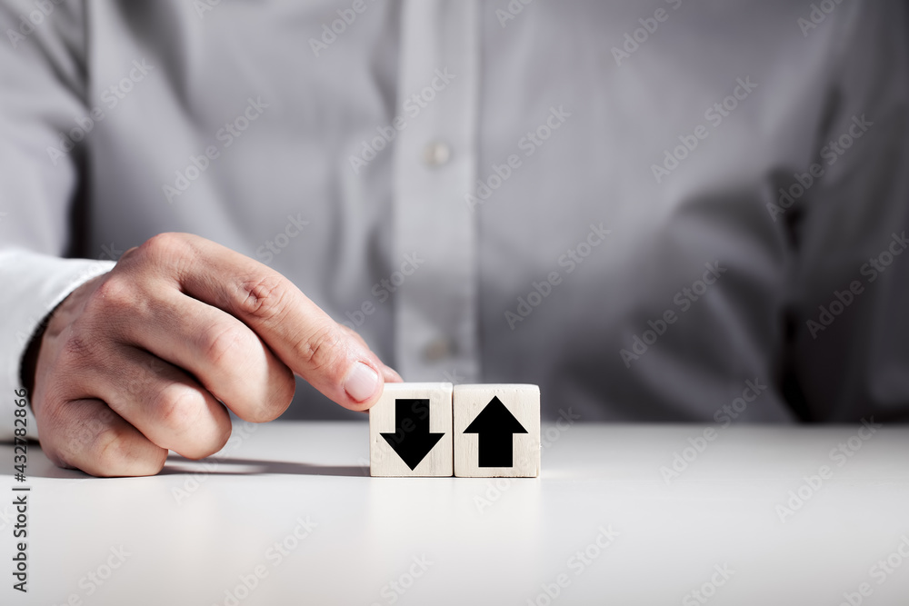 Poster man choosing the wooden cube with down arrow next to the cube with up arrow.