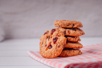 Piles of delicious chocolate chip cookies on a white plate with a milk bottle. Pastry utensils with white linen napkins on a wooden table. Delicious on a white plate with a bottle of milk.