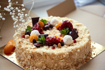 Birthday cake decorated with fruit, pomegranate seeds, chocolae and grapes in he box. Top view. High quality photo
