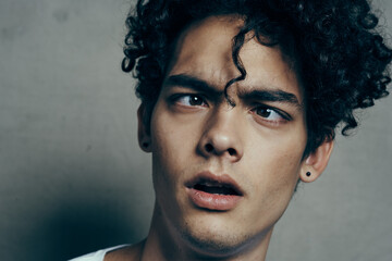 portrait of a handsome guy with curly hair on a gray background white t-shirt close-up model