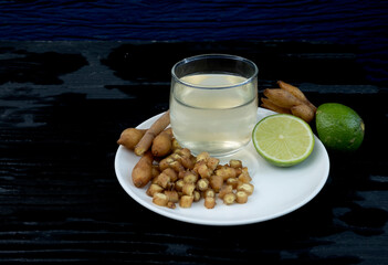 Boesenbergia rotunda, cut into pieces, placed in a white plate with half a lemon and water in a...