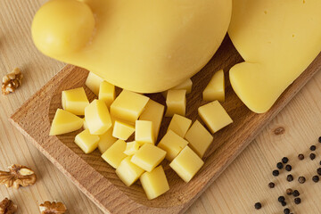 set photo of a typical Italian caciotta, placed on a wooden tray, and cut into cubes. around there are peppercorns, shelled walnuts, olives and yellow cherry tomatoes
