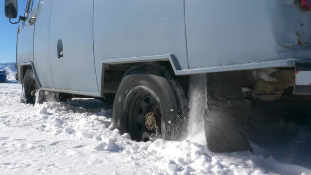 An old minibus skidded in the snow on a bright sunny day
