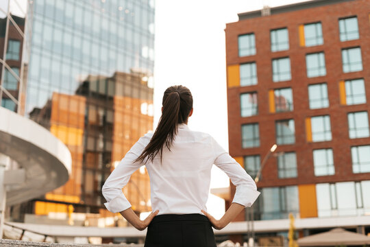 Successful WOMAN WATCHING CONFIDENTLY HER TARGET. Back VIEW OF DETERMINED WOMAN LOOKING TO BIG BUSINESS BUILDINGS.