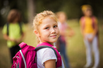 Large group of school kids in nature. Portrait of school girl. Focus is on foreground.  It's time for a little fun after school.