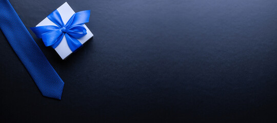 Gift father day. Blue bowtie or tie, white box with bow ribbon on dark background. Happy loving...