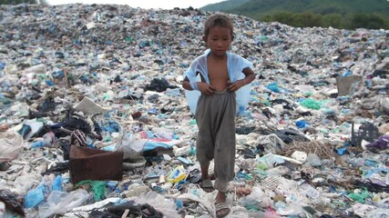 Poor Boy Walking On Garbage Dump
