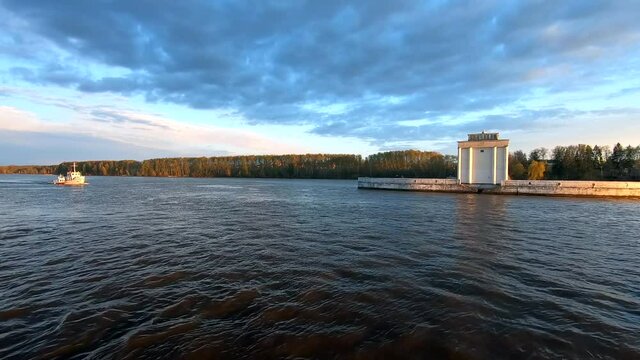 Passing the yacht along the river at sunset. Beautiful colorful landscape of the river against the background of the blue sky at sunset. Traveling by ship on the river.